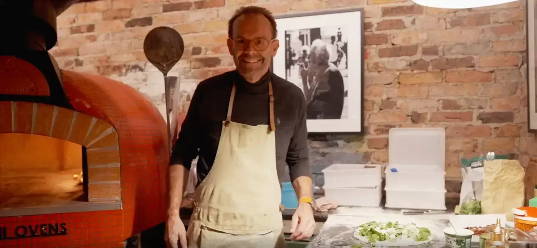 Haakon Ørland smiling at the camera while he makes pizza