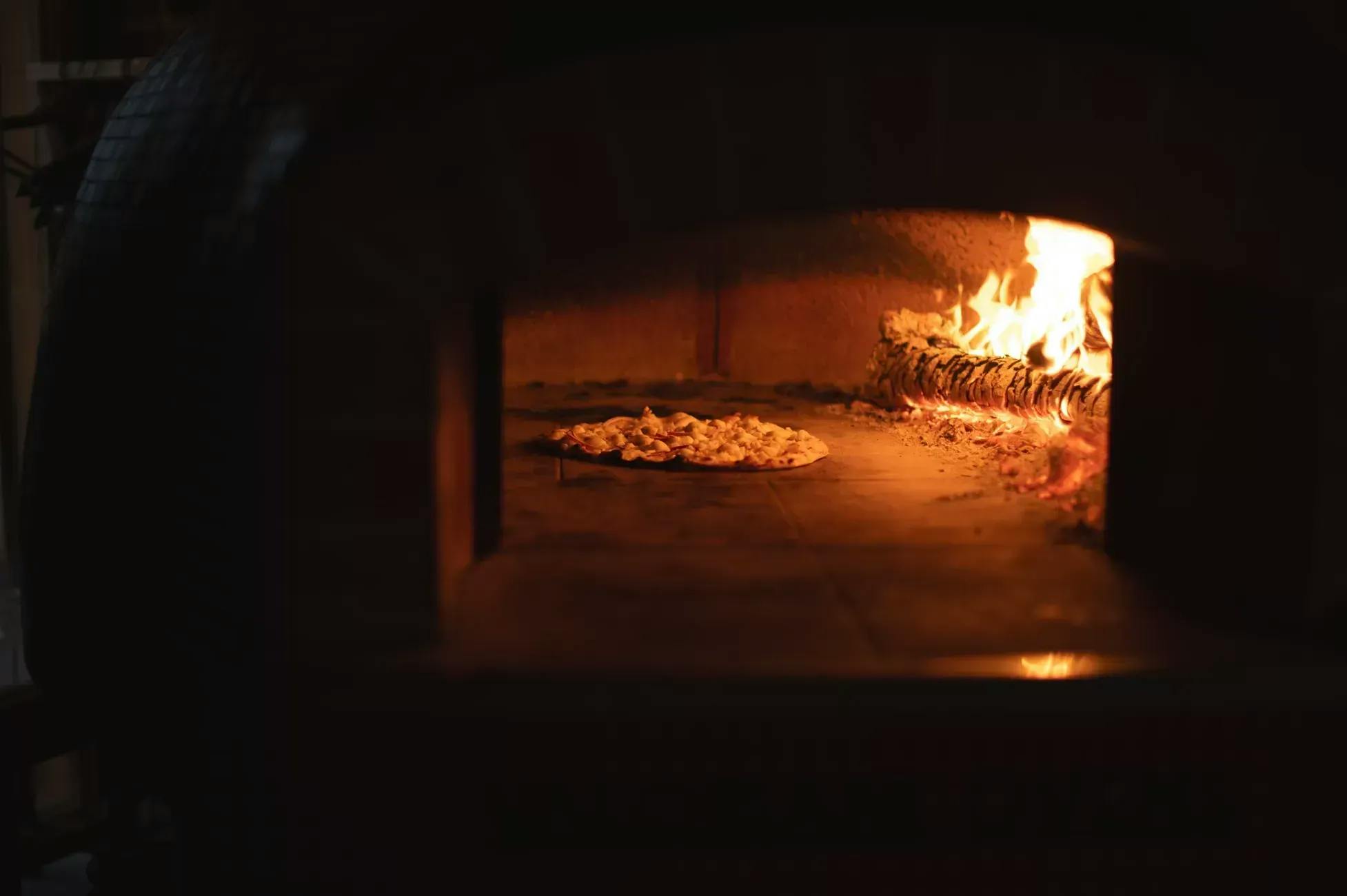 Nærbilde av en pizza inni en italiensk ovn