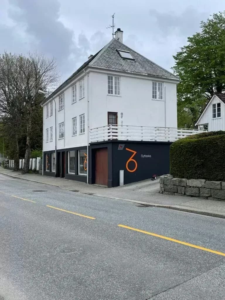 Strandgata 76 seen from the road from Stavanger towards Sandnes. The building has a black garage with the logo of Syttiseks on the side